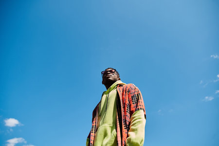 Handsome African American man in colorful jacket stands in lush field.の写真素材