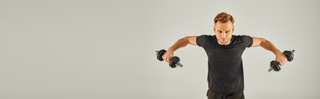 A young sportsman in active wear performs a handstand on a grey background in a studio setting.の写真素材