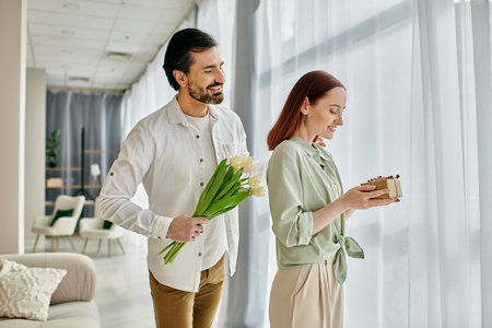 Redhead woman and bearded man standing in modern living room, holding flowers.の写真素材