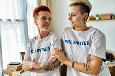 A young lesbian couple, wearing volunteer t-shirts, stands side by side, actively engaging in charity work.の写真素材
