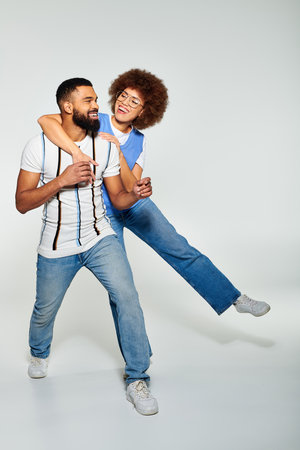 An African American man in stylish clothes carries a woman on his back, showcasing friendship and trust.の写真素材