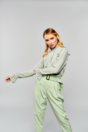 Stylish woman in green outfit striking a pose on gray backdrop.の写真素材