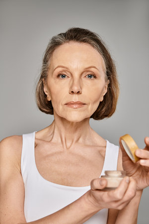 Woman skillfully applying makeup, a cream container.の写真素材