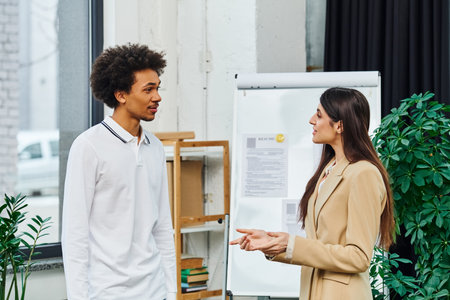 A man and a woman engage in a conversation in an office setting.