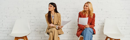 Two women seated gracefully on chairs in a stylish setting.