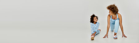 A happy African American mother and daughter in pajamas posing in front of a white background.の写真素材