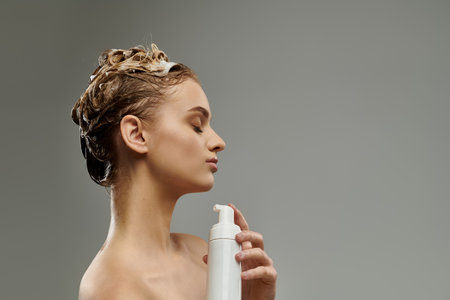 Stylish woman holding spray bottle, caring for wet hair.の写真素材