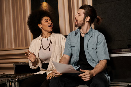 A man and woman collaborate on music in a recording studio, surrounded by instruments and equipment.