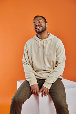 A stylish African American man sitting on a white box.の写真素材
