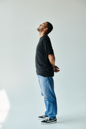 A stylish African American man stands with hands in pockets against a vibrant backdrop.