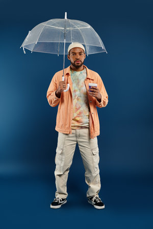 Stylish man holding umbrella and coffee cup against vibrant backdrop.の写真素材