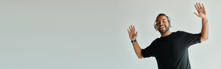 Black-shirted man energetically raises his hands, standing confidently.の写真素材