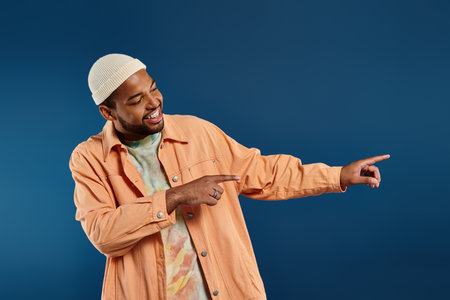 African American man in orange shirt energetically points towards something off-frame.