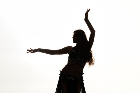 A woman in a belly dance pose with her arms raised gracefully.の写真素材