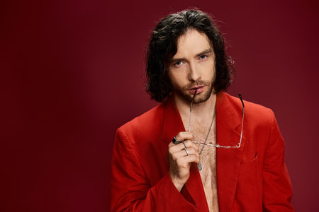 A handsome man in a striking red suit, showcasing confidence and style in a studio setting.