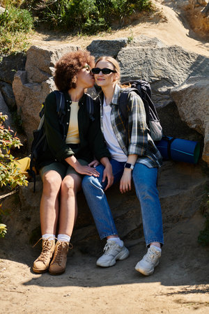 A young lesbian couple enjoys a hike in the wilderness, sharing a tender moment on a rocky outcrop.