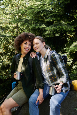 Two young women, one with curly brown hair and one with straight blonde hair, are hiking in the woods together.の写真素材