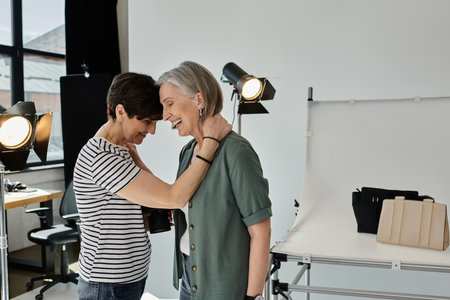 A middle-aged lesbian couple stands confidently in a modern photo studio, posing in front of a...