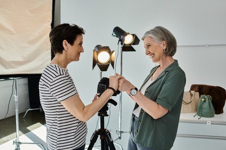 two women, lesbian couple, holding hands while standing together in studioの写真素材