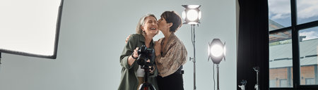 A middle-aged lesbian couple kissing near camera in a photo studio