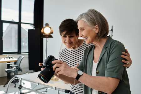 A middle-aged lesbian couple in a modern studio passionately holding a cameraの写真素材