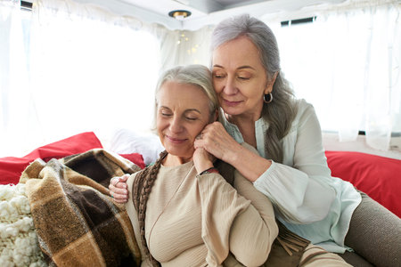Two middle-aged lesbian women share a tender moment inside their camper van during a road trip.の写真素材