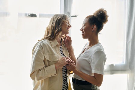 A lesbian couple enjoys a moment of intimacy at home, bathed in warm sunlight.の写真素材