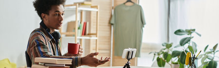 Young African American blogger on phone camera at desk with coffee.の写真素材