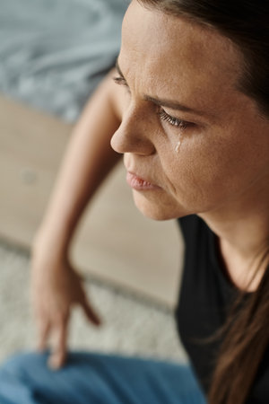 A middle-aged woman sits and cries, struggling with depression.