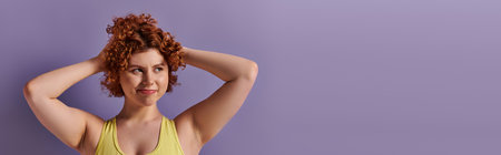 A young, curvy redhead woman in yellow underwear striking a pose against a vibrant purple...