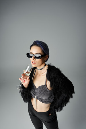 Pretty young woman with short dyed hair posing confidently in a stylish bra top and black pants in a studio setting.の写真素材