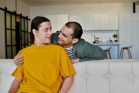 A young gay couple shares a tender moment in a modern apartment, showing their love and connection.の写真素材