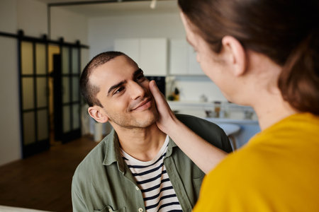 A young gay couple enjoys a moment of intimacy in a modern apartment.の写真素材