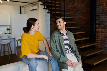 A young gay couple relaxes in their modern apartment, enjoying each others company.の写真素材