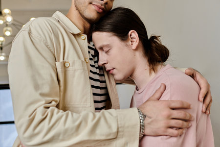 A young gay couple embraces in a modern apartment, showcasing a tender moment of intimacy and...