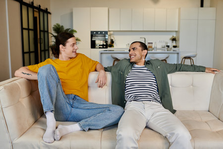 A young gay couple relaxes on a white sofa in a modern apartment, enjoying a moment of quiet together.の写真素材