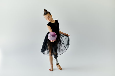 A young gymnast with a prosthetic leg performs a graceful routine with a purple ball.の写真素材