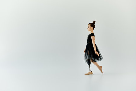 A young girl with a prosthetic leg practices her ballet steps in a studio.の写真素材