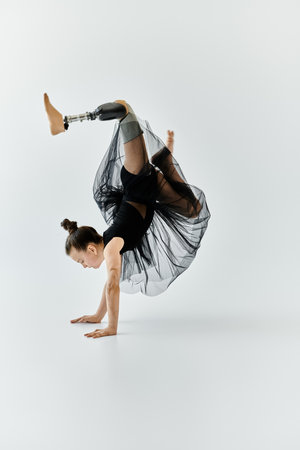 A young girl with a prosthetic leg performs a graceful handstand in a gymnastics studio.の写真素材