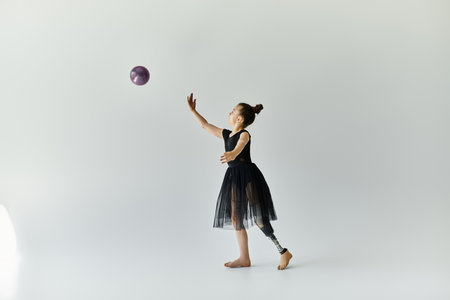 A young girl with a prosthetic leg performs a gymnastics routine with a ball.の写真素材