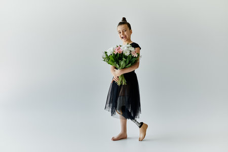 A young girl with a prosthetic leg stands in a studio holding a bouquet of flowers.の写真素材