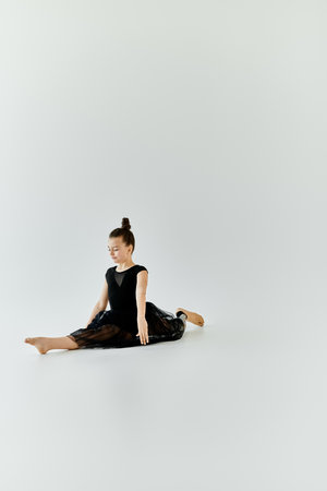 A young girl with a prosthetic leg stretches on the floor in a white studio.の写真素材