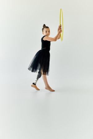 A young girl with a prosthetic leg practices gymnastics with a hula hoop in a studio setting.の写真素材