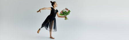 A young gymnast with a prosthetic leg performs a graceful pose while holding a bouquet of flowers.の写真素材