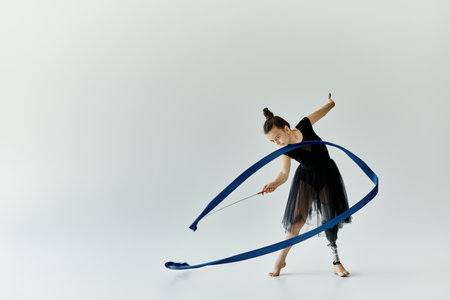 A young girl with a prosthetic leg performs a graceful gymnastics routine with a ribbon.の写真素材