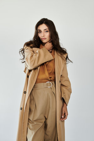 A young woman showcases her autumn style in a chic outfit, exuding confidence and elegance against a minimalistic backdrop.の写真素材