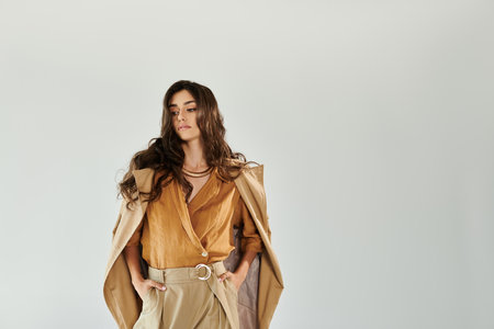 A young and beautiful woman exudes confidence in a trendy autumn outfit, perfectly styled for the season in a modern studio.の写真素材