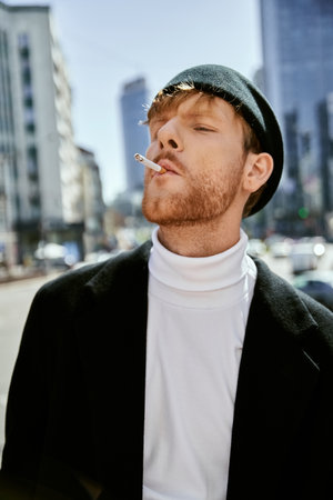 Stylish redhead man smoking a cigarette in the city.の写真素材