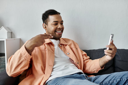 An African American man smiles and signs with his hand while sitting on a couch.の写真素材