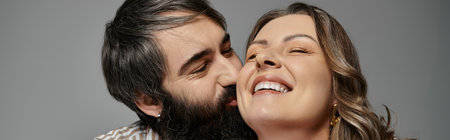 A couple in elegant attire shares a tender moment, the woman laughing as her partner leans in for a kiss.の写真素材